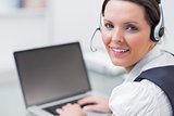 Portrait of business woman wearing headset and using laptop
