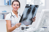 Female doctor with xray sitting in front of computer at clinic
