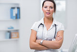 Confident female doctor with arms crossed at clinic
