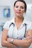 Confident female doctor with arms crossed at clinic