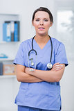 Confident female surgeon with arms crossed at clinic