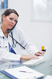 Female doctor using computer while on call at clinic