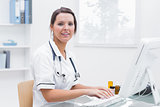 Smiling female nurse using computer at clinic