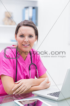 Portrait of smiling nurse with laptop at clinic