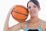 Portrait of happy woman holding basketball on shoulder