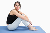 Side view of young woman in sportswear sitting on yoga mat