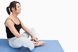 Side view of woman sitting in yoga position on exercise mat