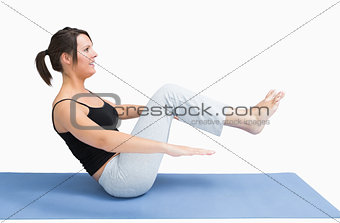 Side view of young woman exercising on yoga mat