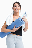 Portrait of woman in sportswear holding water bottle and mat