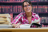 Female college student sitting with books at library