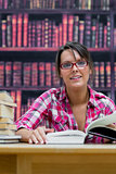 Female college student sitting with books at library
