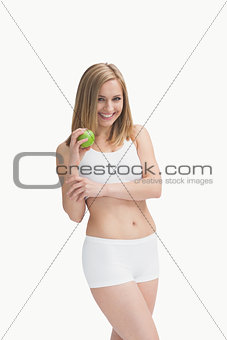 Portrait of happy young woman showing a green apple