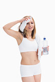 Sporty woman holding water bottle and wiping sweat with a towel