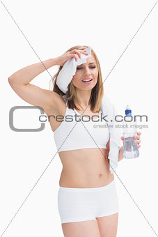 Sporty woman holding water bottle and wiping sweat with a towel