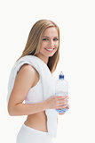Portrait of smiling young woman with towel around neck holding water bottle