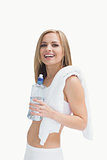 Portrait of happy woman with towel holding water bottle