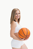 Portrait of happy woman in sportswear holding basketball