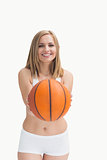 Happy woman in sportswear holding out basketball