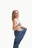 Woman wearing old pants after losing weight and gesturing thumbs up