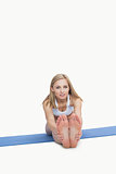 Portrait of young woman performing stretching exercise on yoga mat