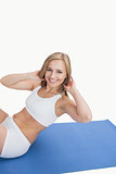 Portrait of happy young woman doing situps on exercise mat