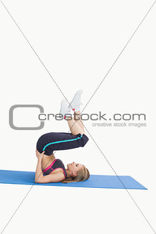 Side view of young woman in the shoulder stand position on yoga mat
