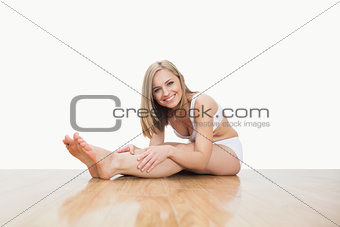 Portrait of young woman stretching on hardwood floor