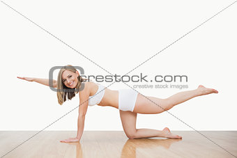 Portrait of young woman in yoga pose on hardwood floor