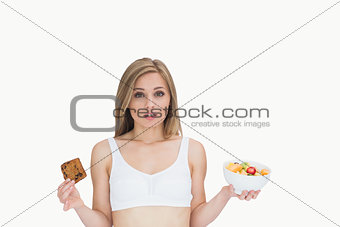 Portrait of young woman holding cookie and fruit bowl