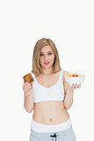Portrait of young woman holding cookie and fruit bowl