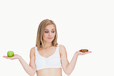 Young woman with apple looking at cookie
