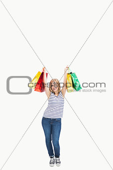 Portrait of cute excited young woman holding up shopping bags