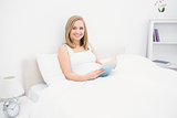 Portrait of happy woman reading book in bed