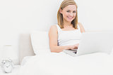 Portrait of happy relaxed woman using laptop in bed