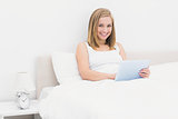 Portrait of smiling woman using digital tablet in bed