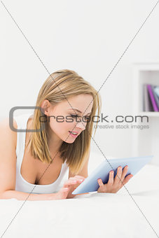 Beautiful woman lying in bed and using digital tablet