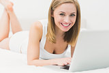 Portrait of beautiful happy woman using laptop in bed