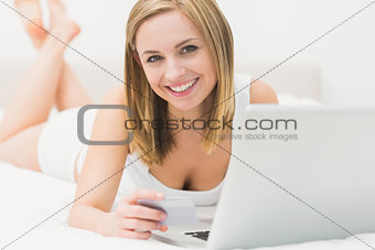 Portrait of woman doing online shopping in bed