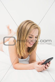 Casual woman with smartphone in bed