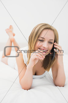 Casual young woman using mobile phone in bed