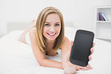 Portrait of casual woman showing new smartphone in bed