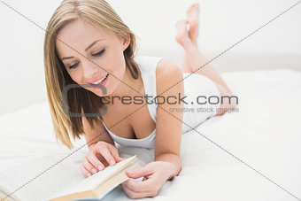Young woman reading book in bed