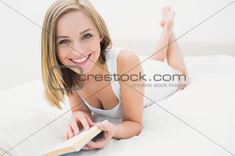 Portrait of young woman reading book in bed