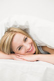 Closeup of young woman under sheet in bed