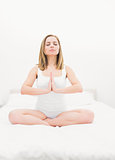 Woman in praying position with eyes closed on bed