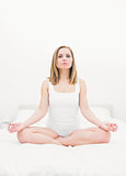 Woman sitting in lotus position on bed