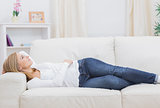 Casual thoughtful woman lying on sofa
