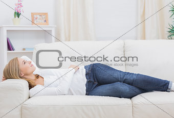 Casual thoughtful woman lying on sofa
