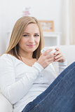 Portrait of woman with coffee cup sitting on couch