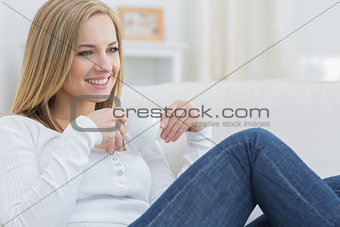 Woman with coffee cup day dreaming on couch